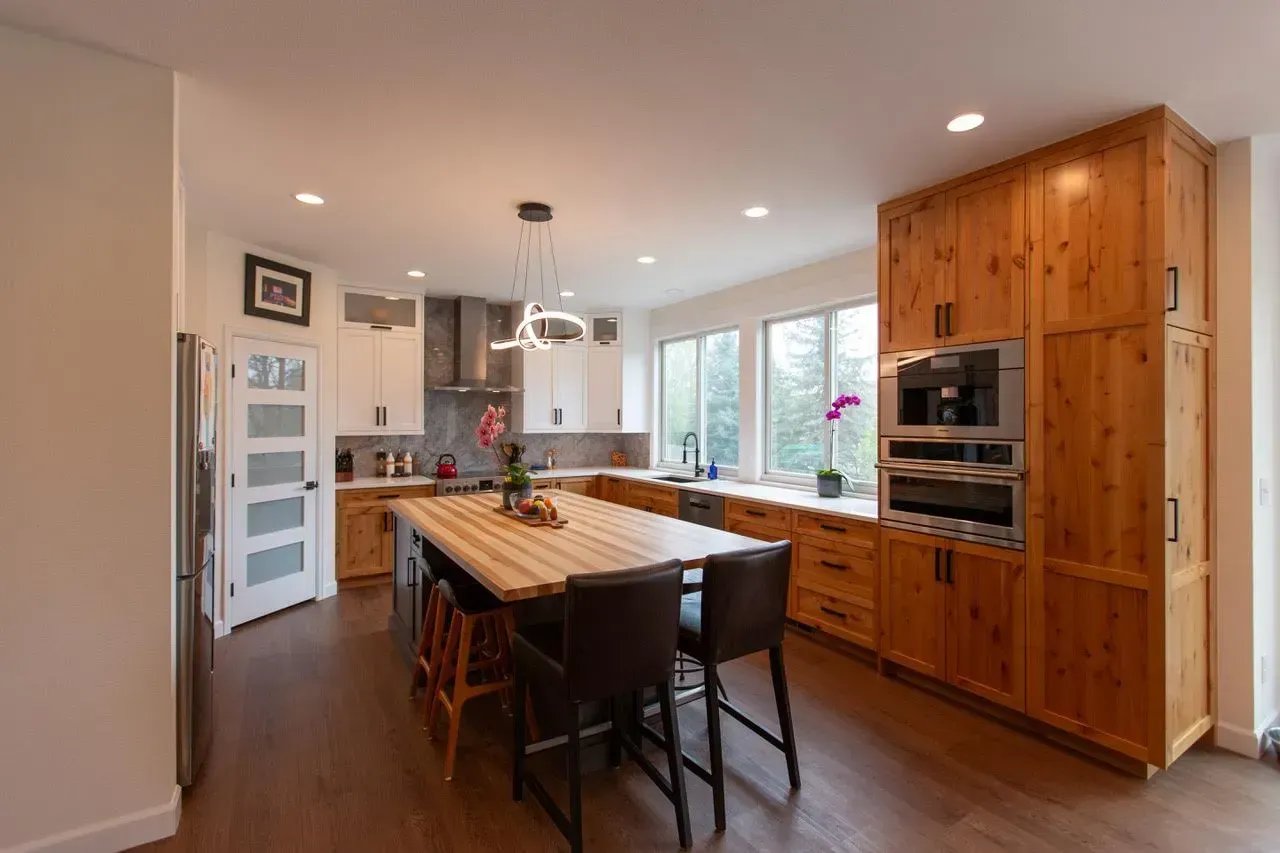 A kitchen with wooden cabinets and a large island in the middle.