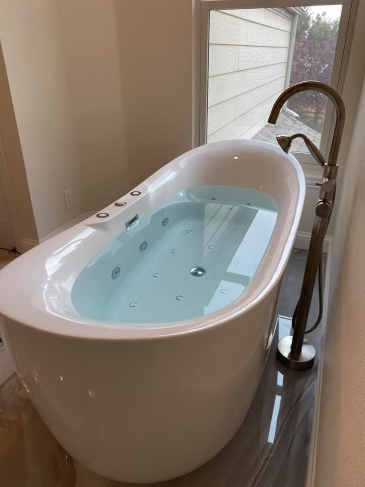 A bathtub filled with water in a bathroom next to a window.