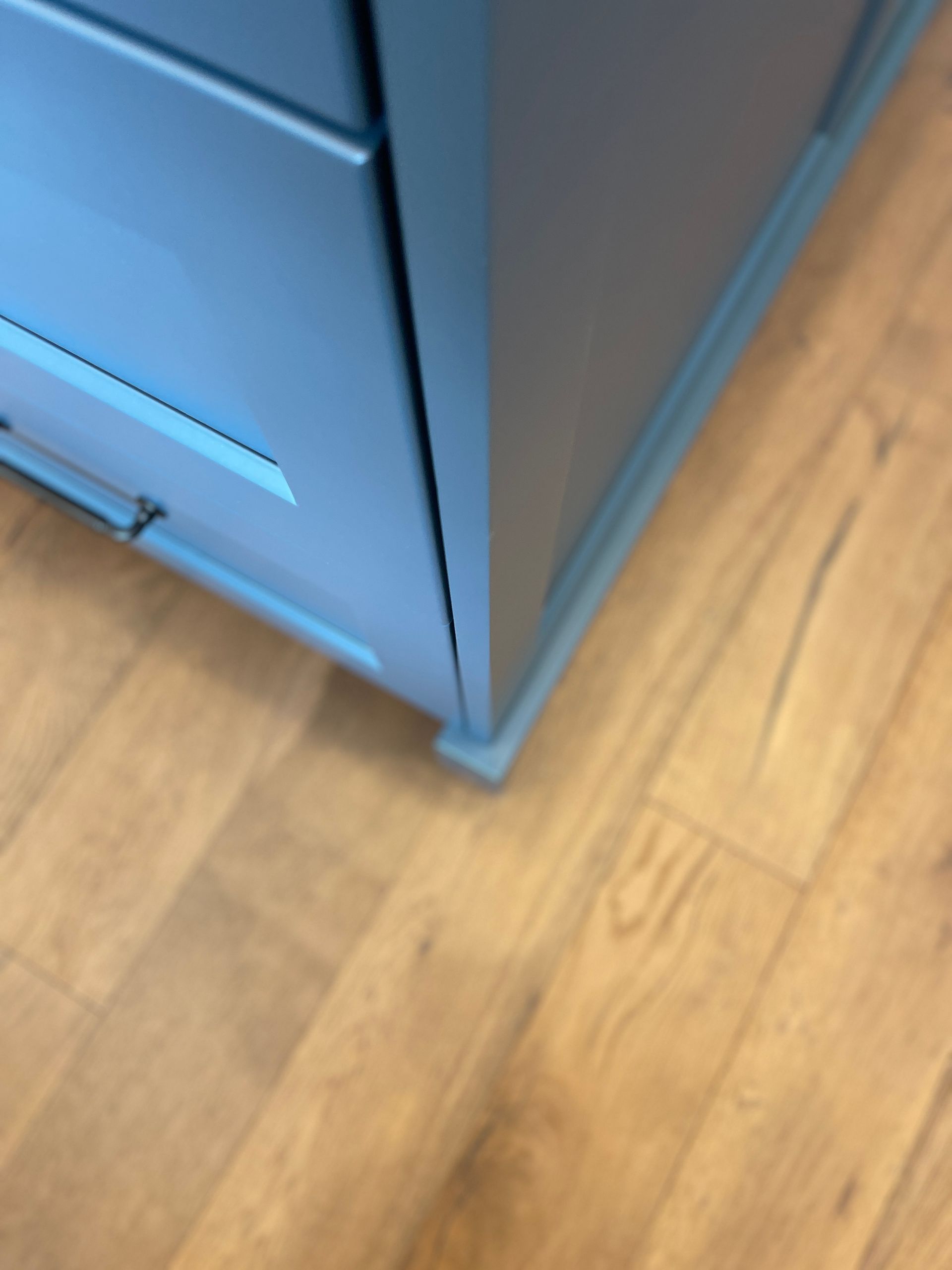 A wooden floor with a blue cabinet in the corner