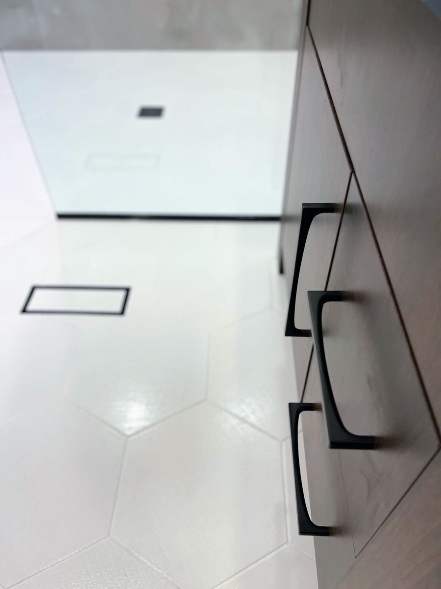 A bathroom with white tiles and black handles