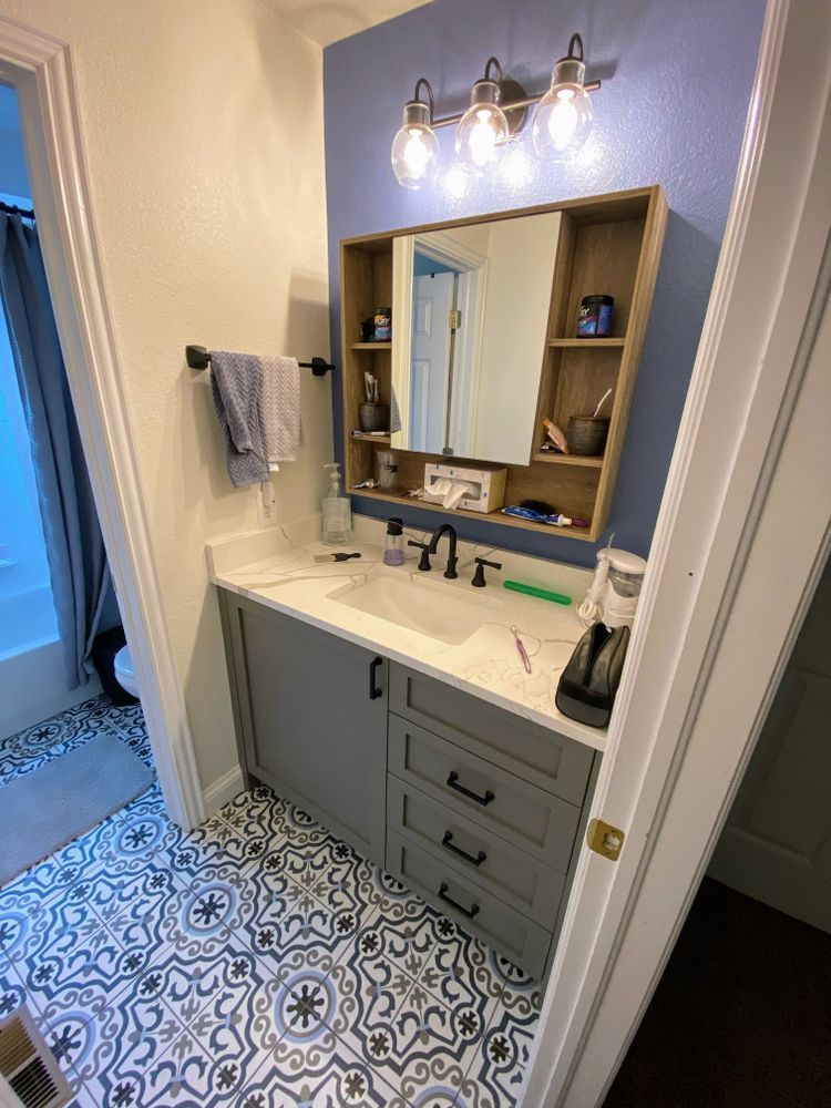 A bathroom with a sink , mirror and tile floor.