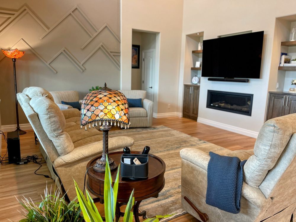 A living room with a couch , chairs , a lamp and a flat screen tv.