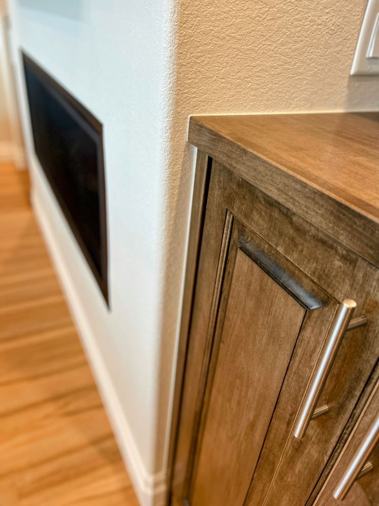 A close up of a wooden cabinet next to a fireplace in a living room.