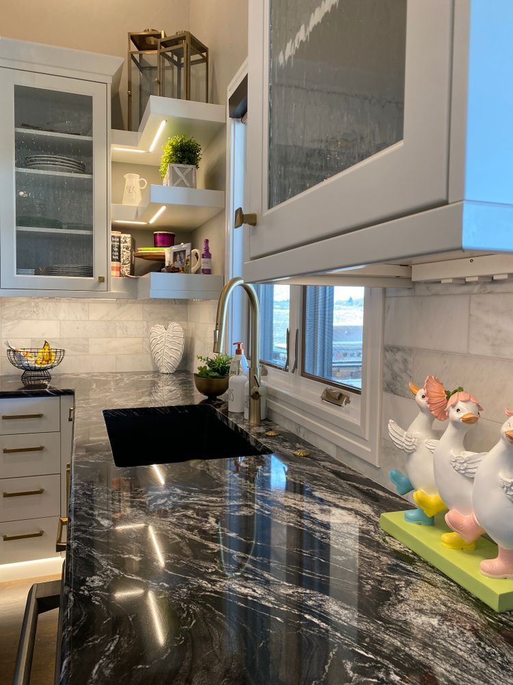 A kitchen with black granite counter tops and white cabinets