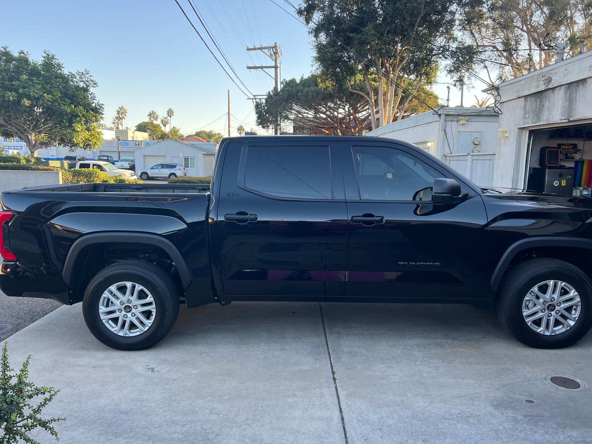 Black Toyota Tundra truck parked outside, side view, under a partly cloudy sky.
