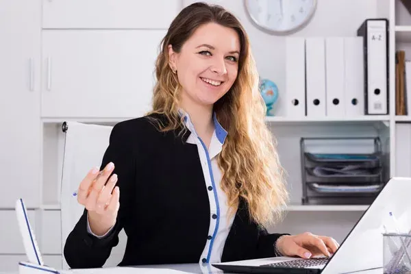 A woman is sitting at a desk in front of a laptop computer.