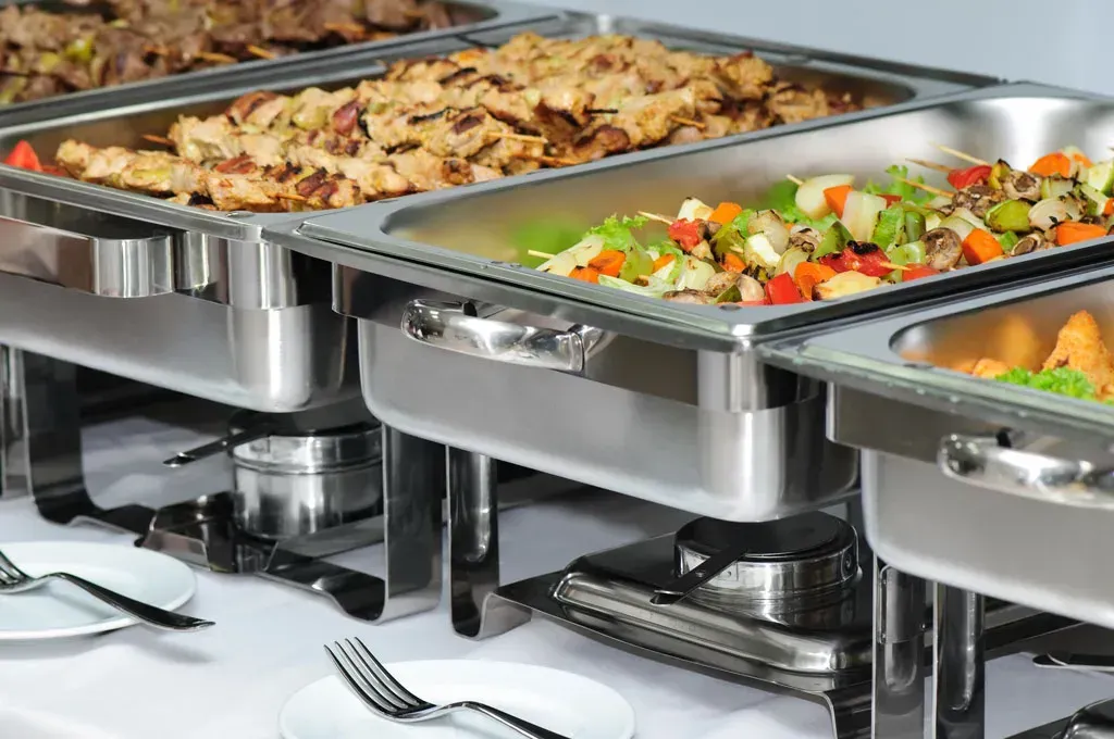 A buffet table with a variety of food in stainless steel trays.