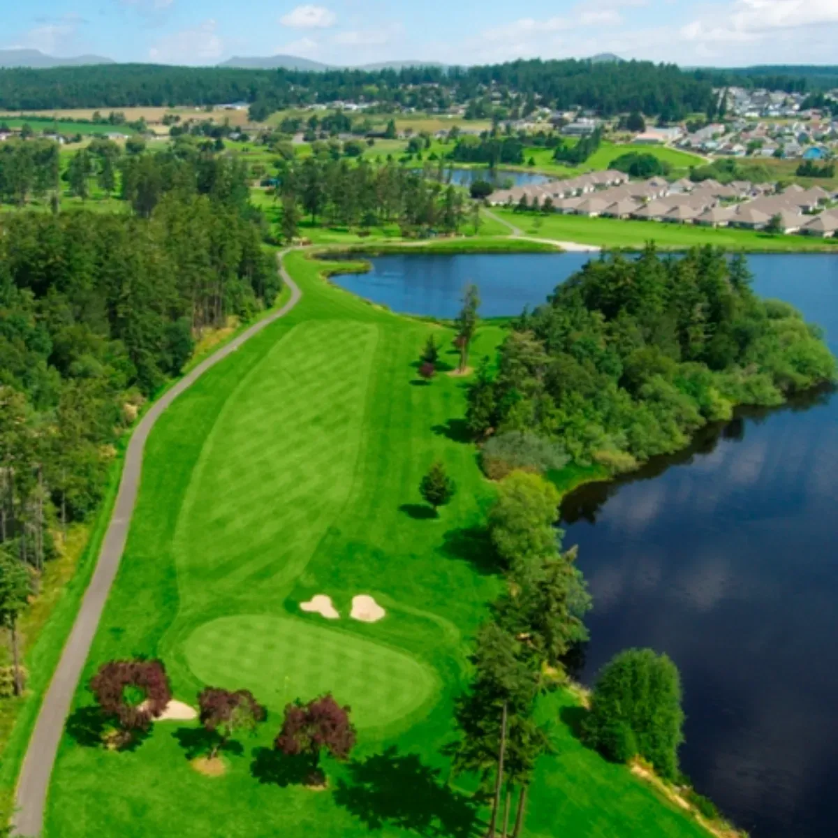 An aerial view of a golf course with a lake in the background