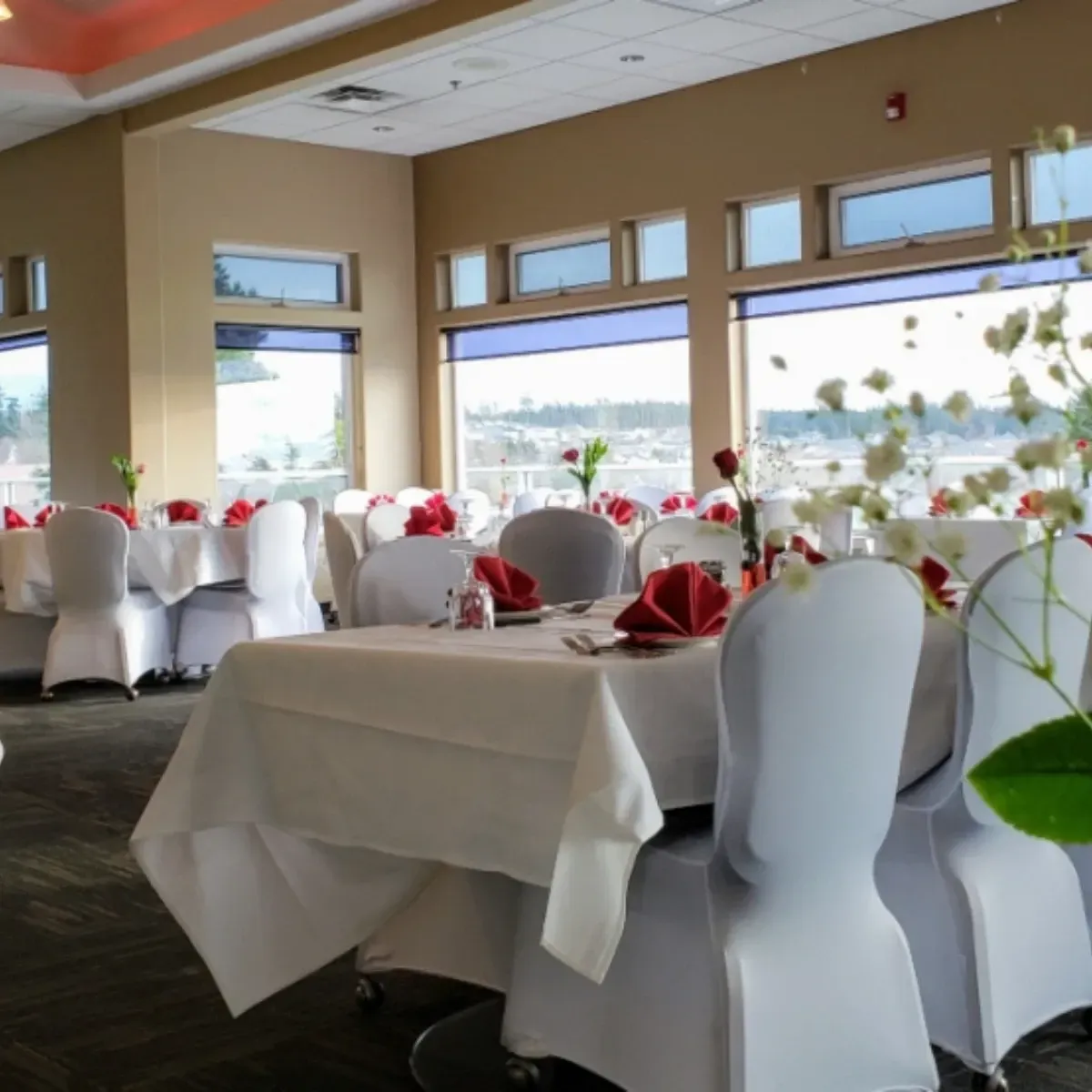 A large room with tables and chairs set up for a wedding reception