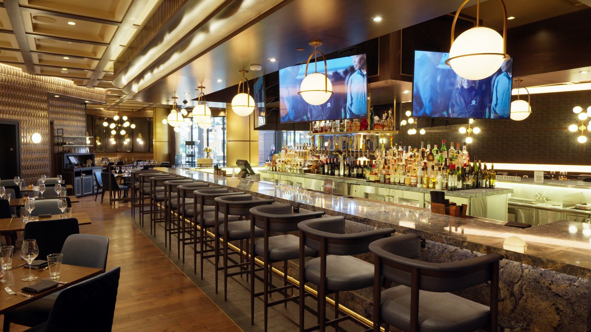 Modern restaurant bar interior with pendant lights, stools, and glowing shelves of bottles