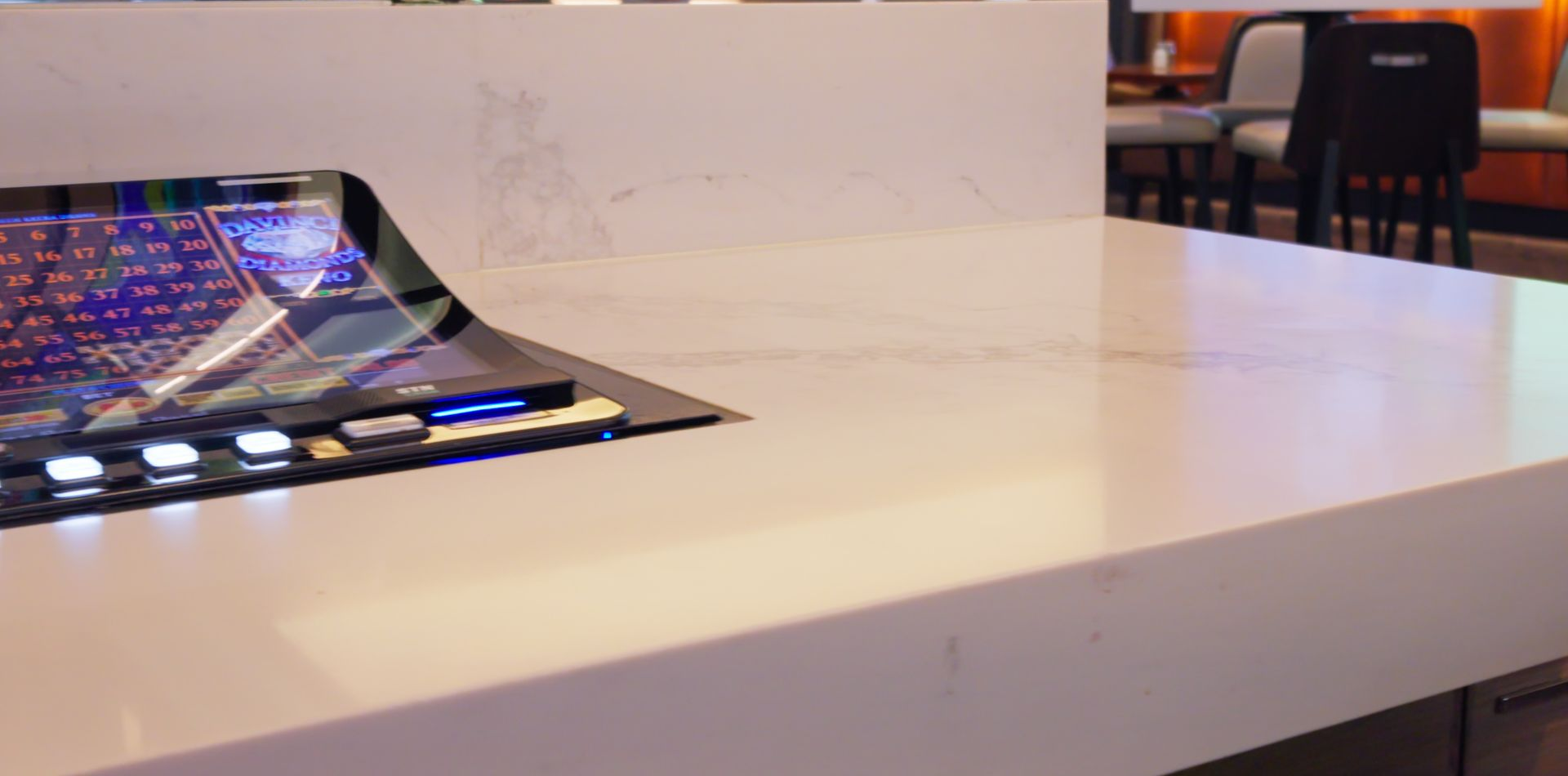 White conference table with a glowing touchscreen device and chairs in the background