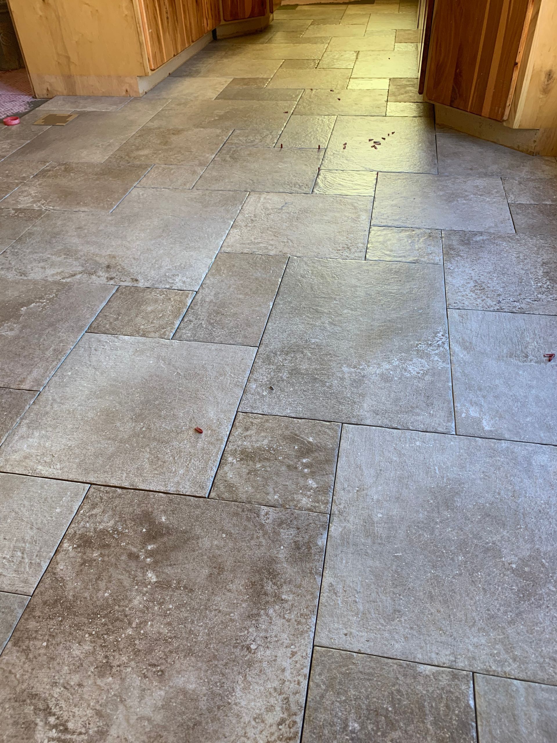 Stone-tiled hallway floor with uneven, worn gray and beige tiles