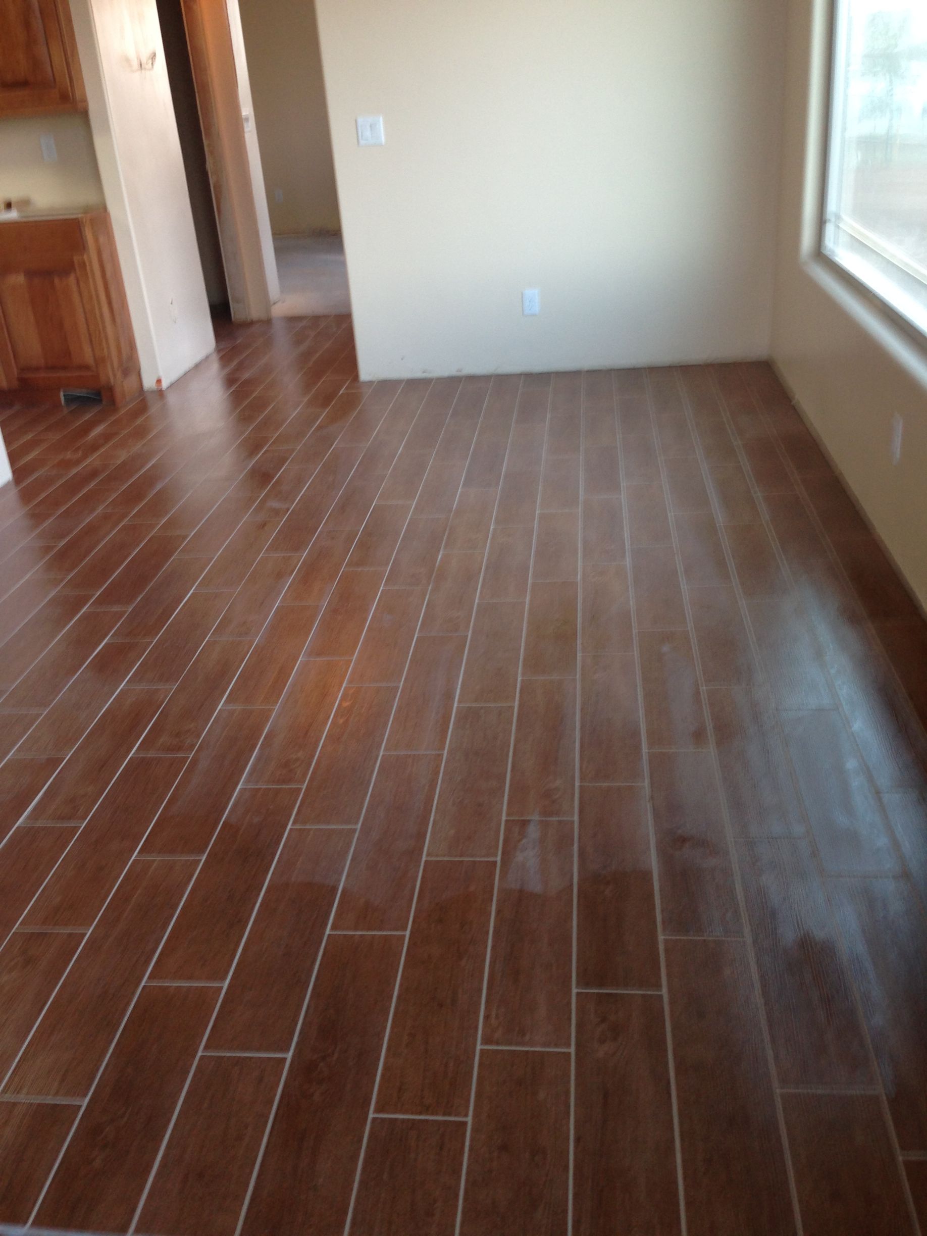 Empty room with brown wood flooring, beige walls, and a large window on the right.