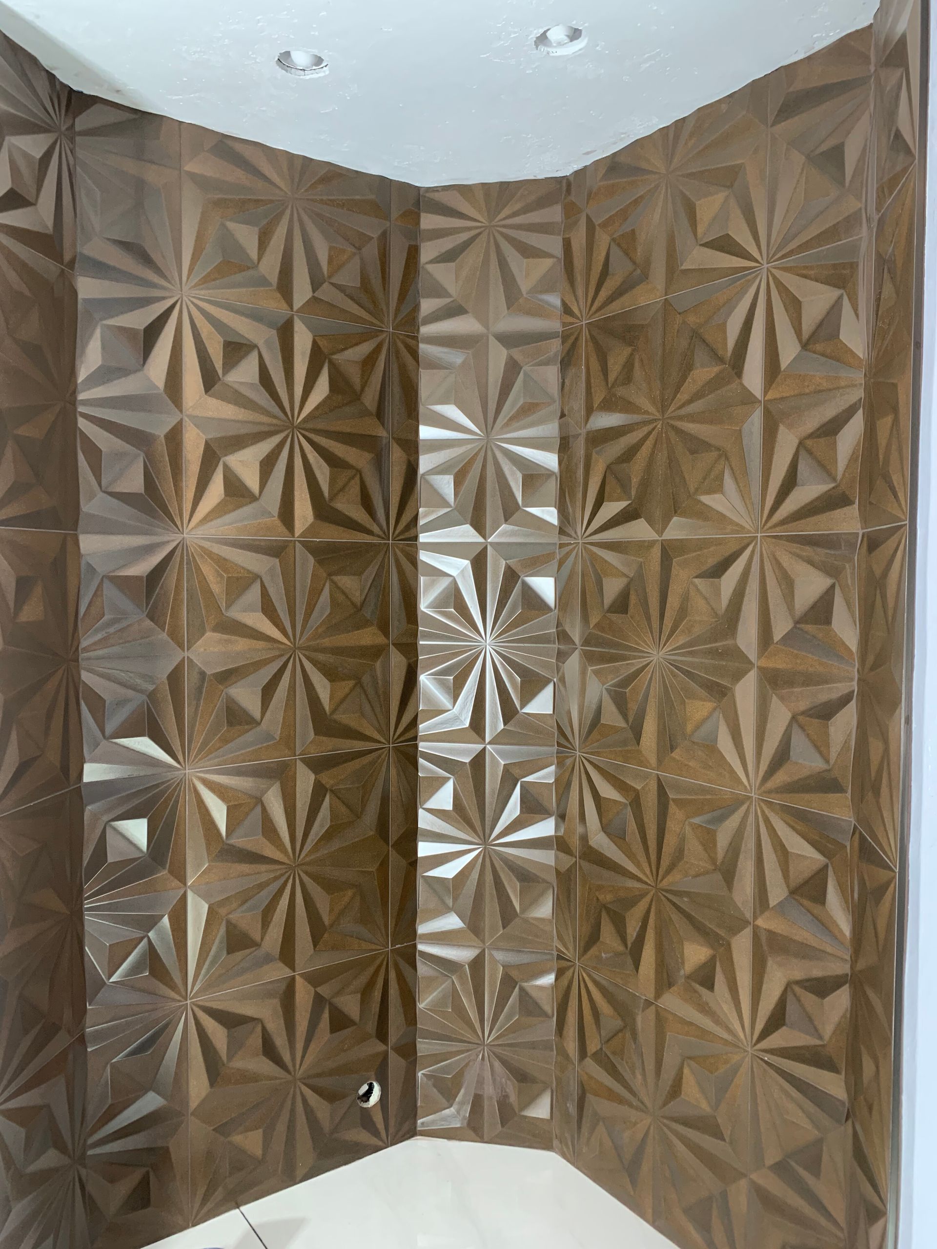 Brown 3D geometric wall panels meeting at a corner beneath a white ceiling