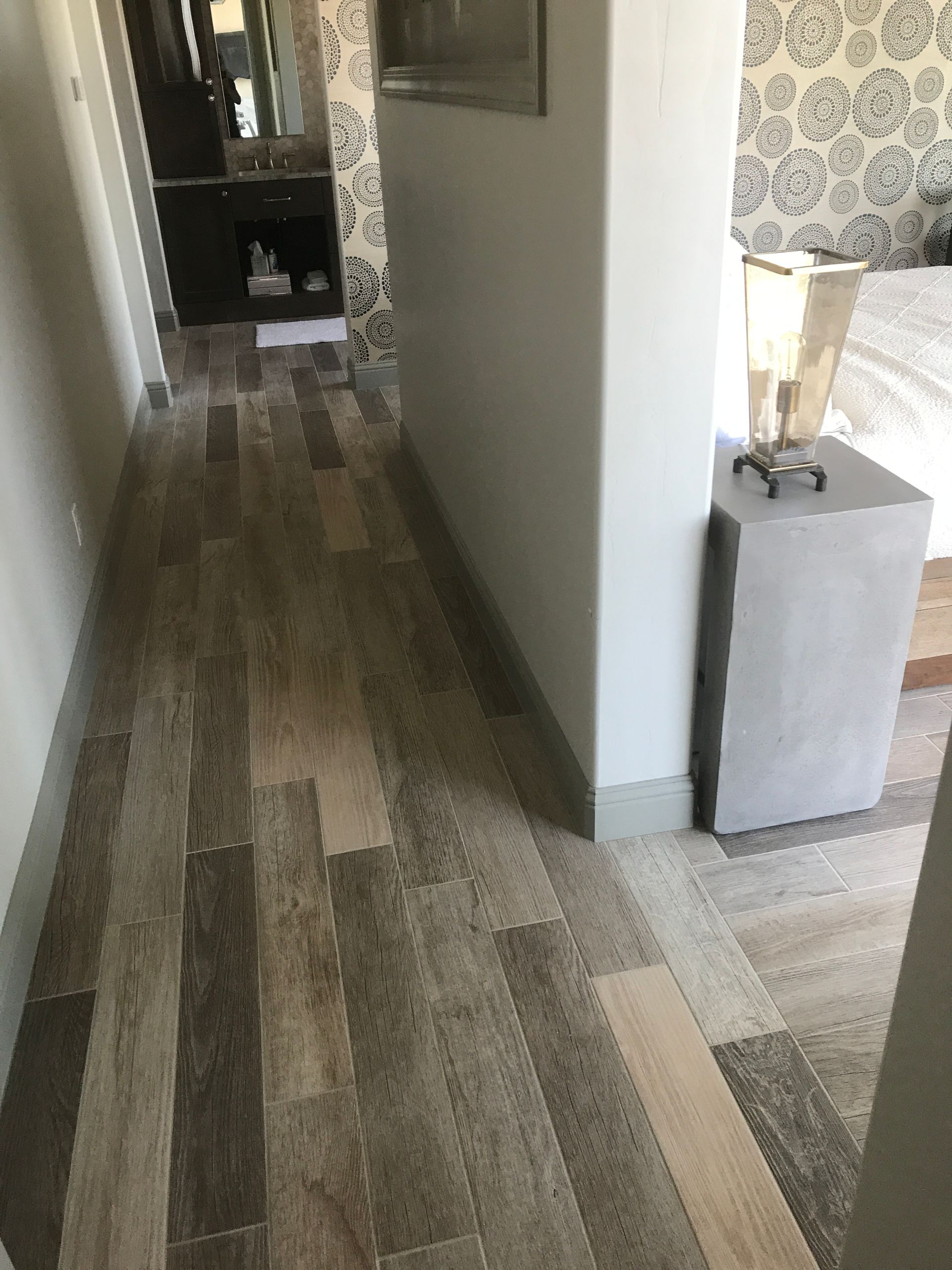 Narrow hallway with wood flooring, white walls, and a small gray cabinet near the corner.