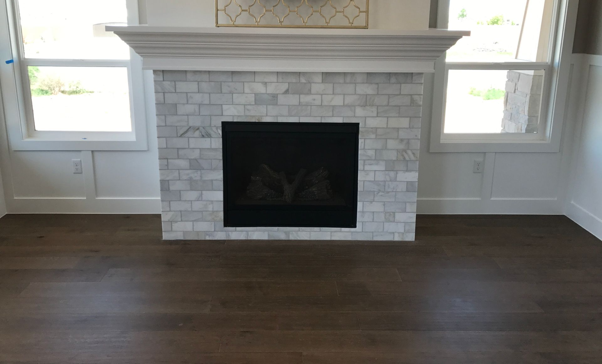 Living room with white brick fireplace, dark wood floor, and two windows with built-in shelves