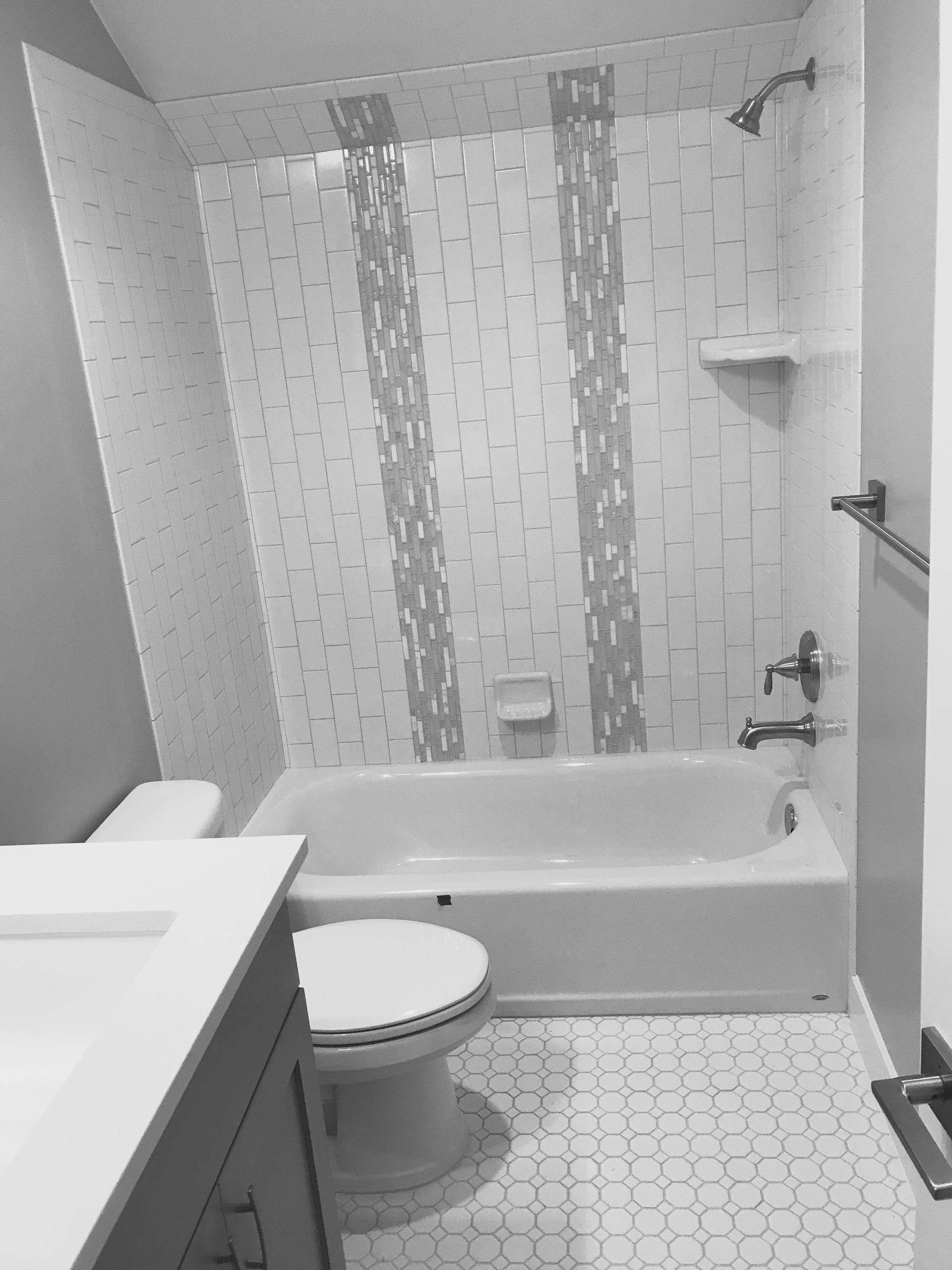 Small white bathroom with tub, toilet, sink, shower curtain, and tiled floor.