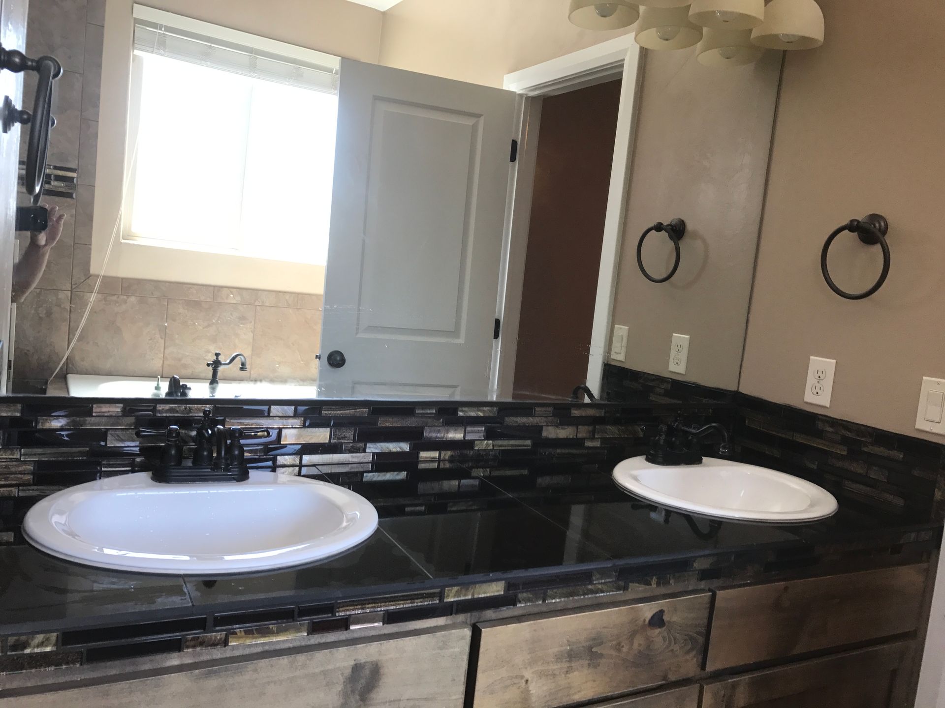 Bathroom vanity with two white sinks, black granite countertop, mirror, and open door.