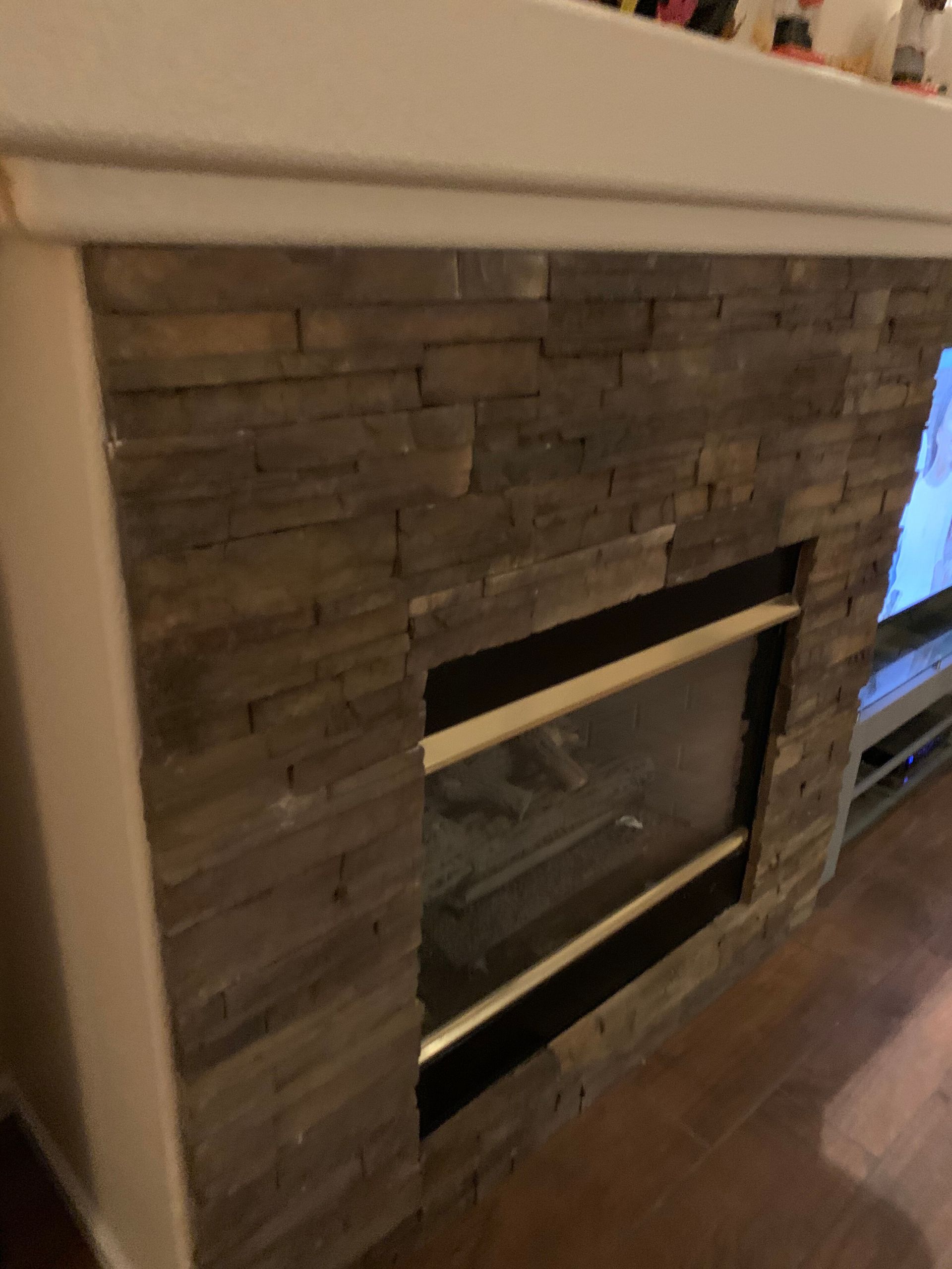 Stone fireplace with a white mantel and a black glass insert in a living room.