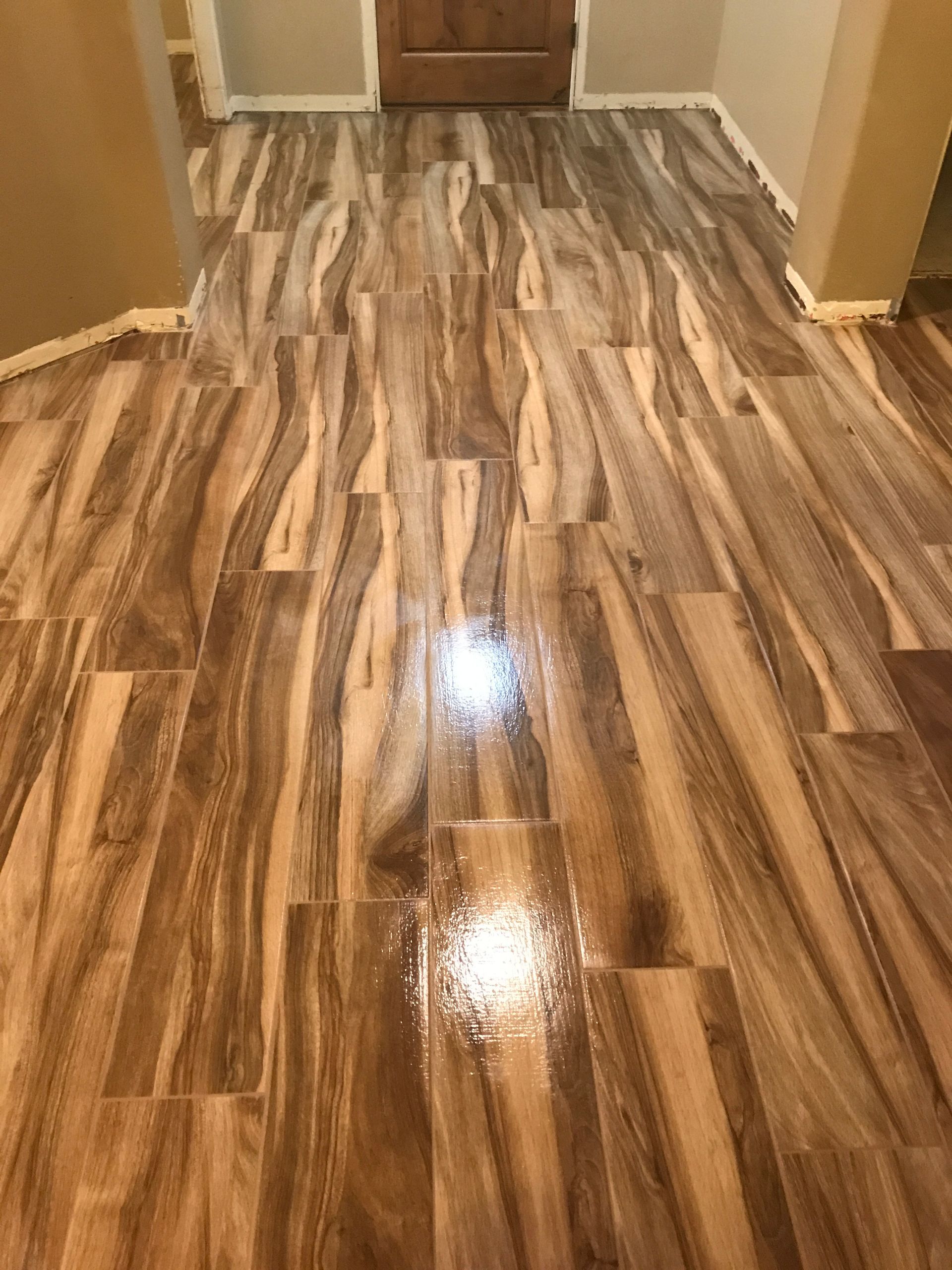 Shiny wood-look hallway floor leading to a closed wooden door