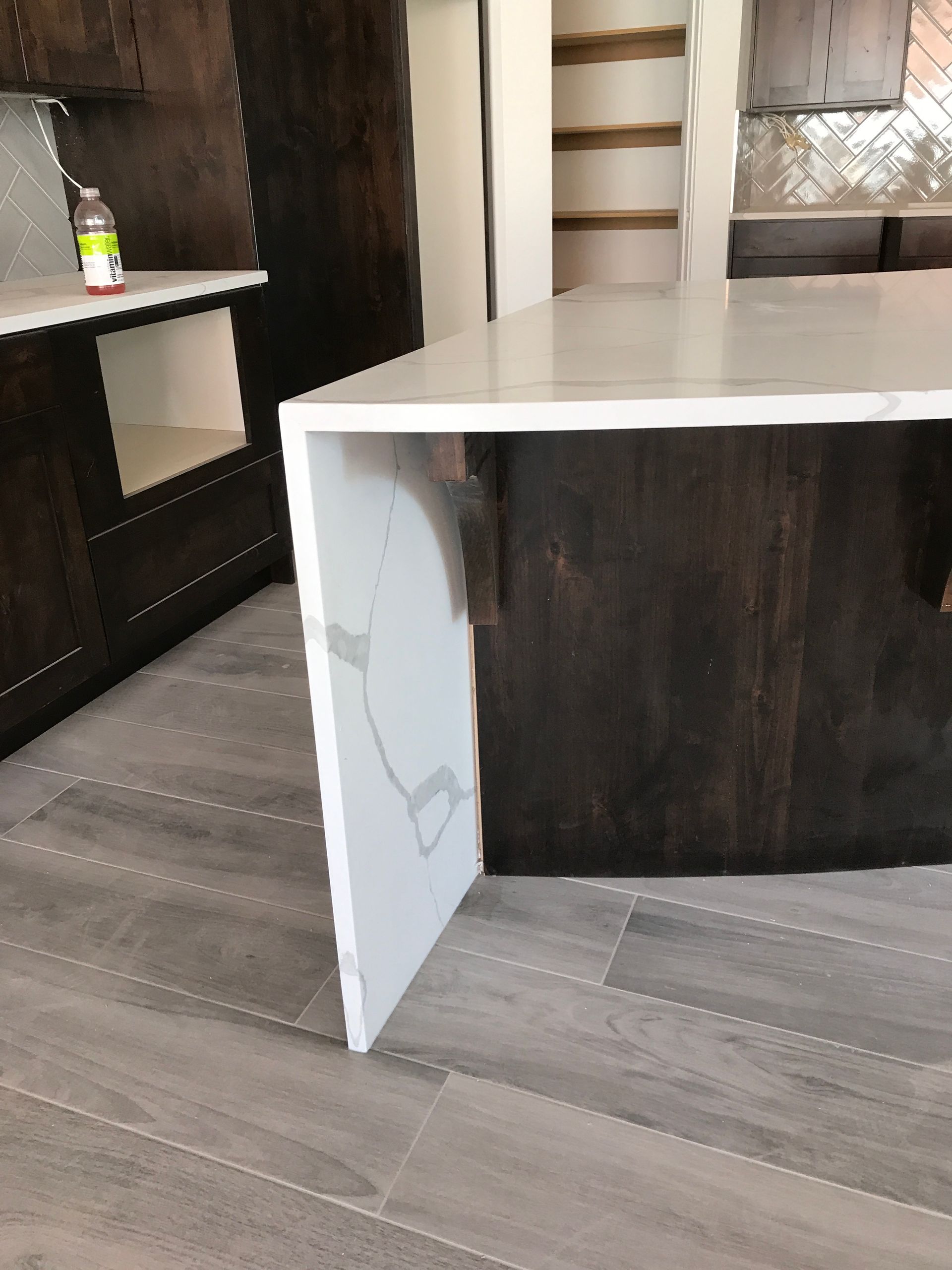 Open cabinet door under a dark wood countertop in a modern kitchen.