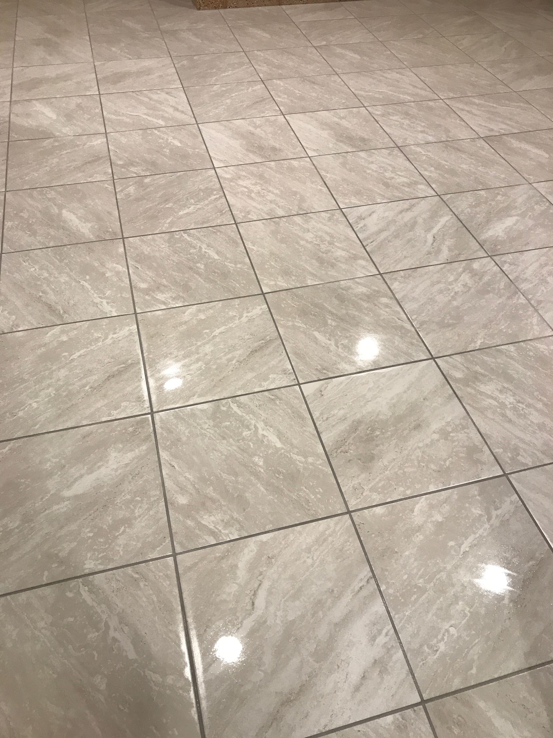 Glossy beige tiled floor with reflections from overhead lights
