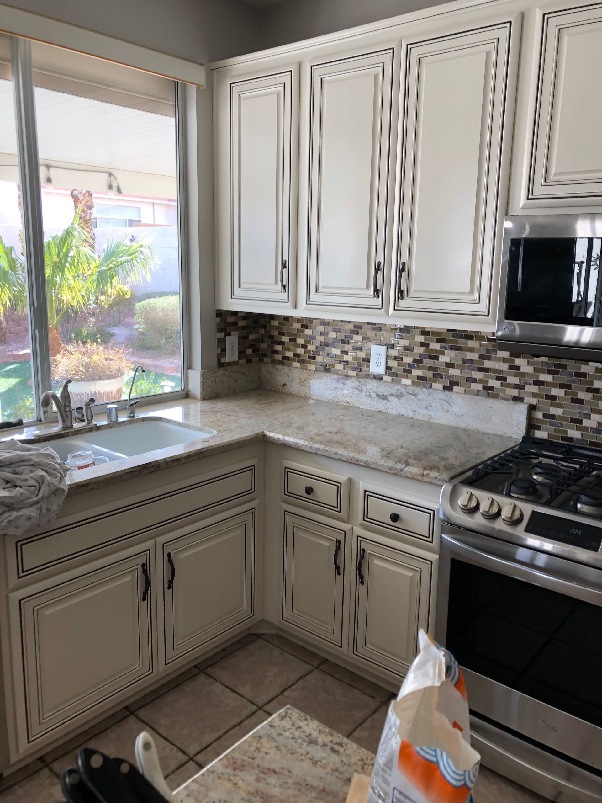Small kitchen with white cabinets, granite countertops, window over sink, and stainless steel stove.