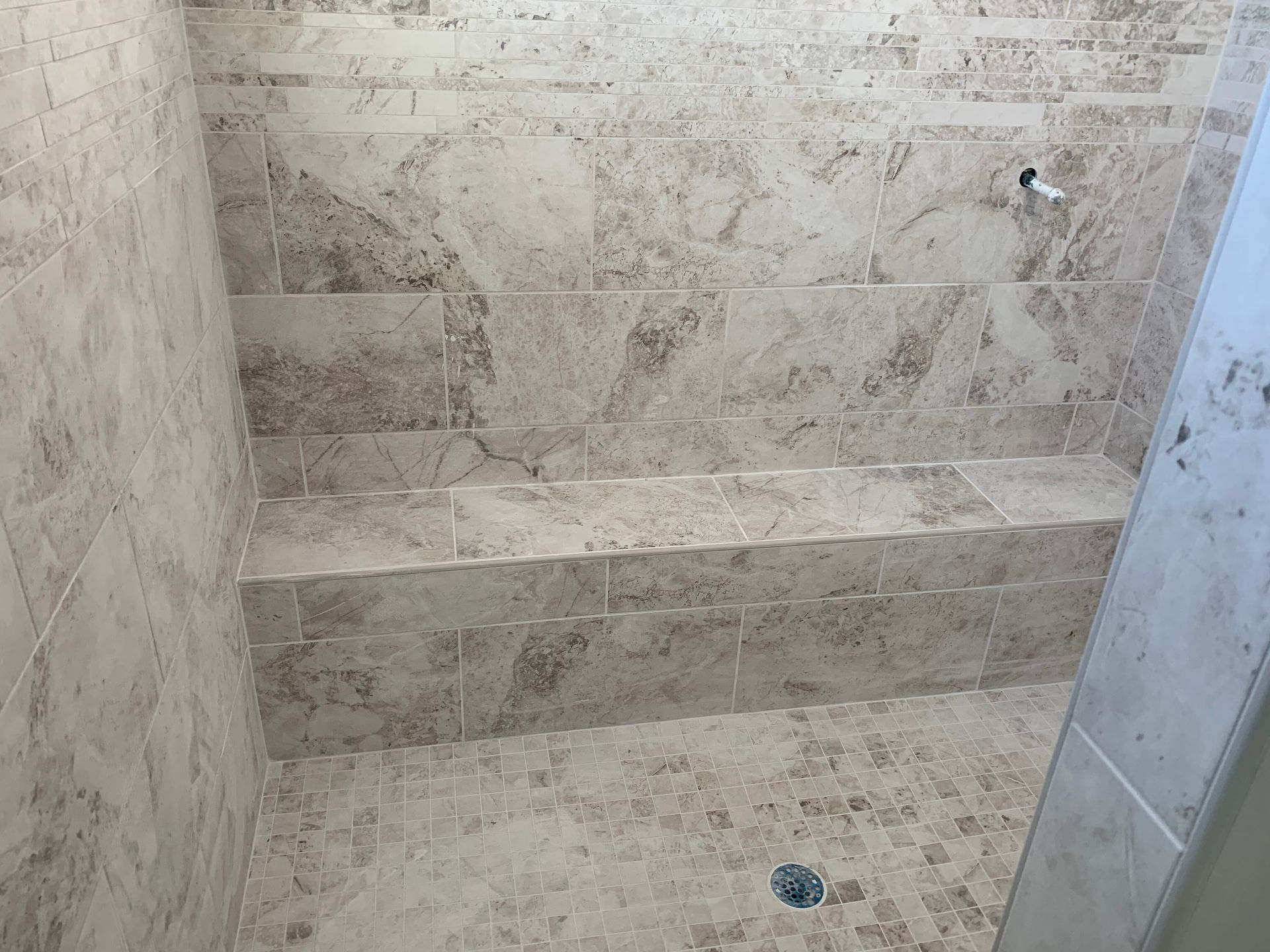 Marble-tiled walk-in shower with built-in bench and floor drain