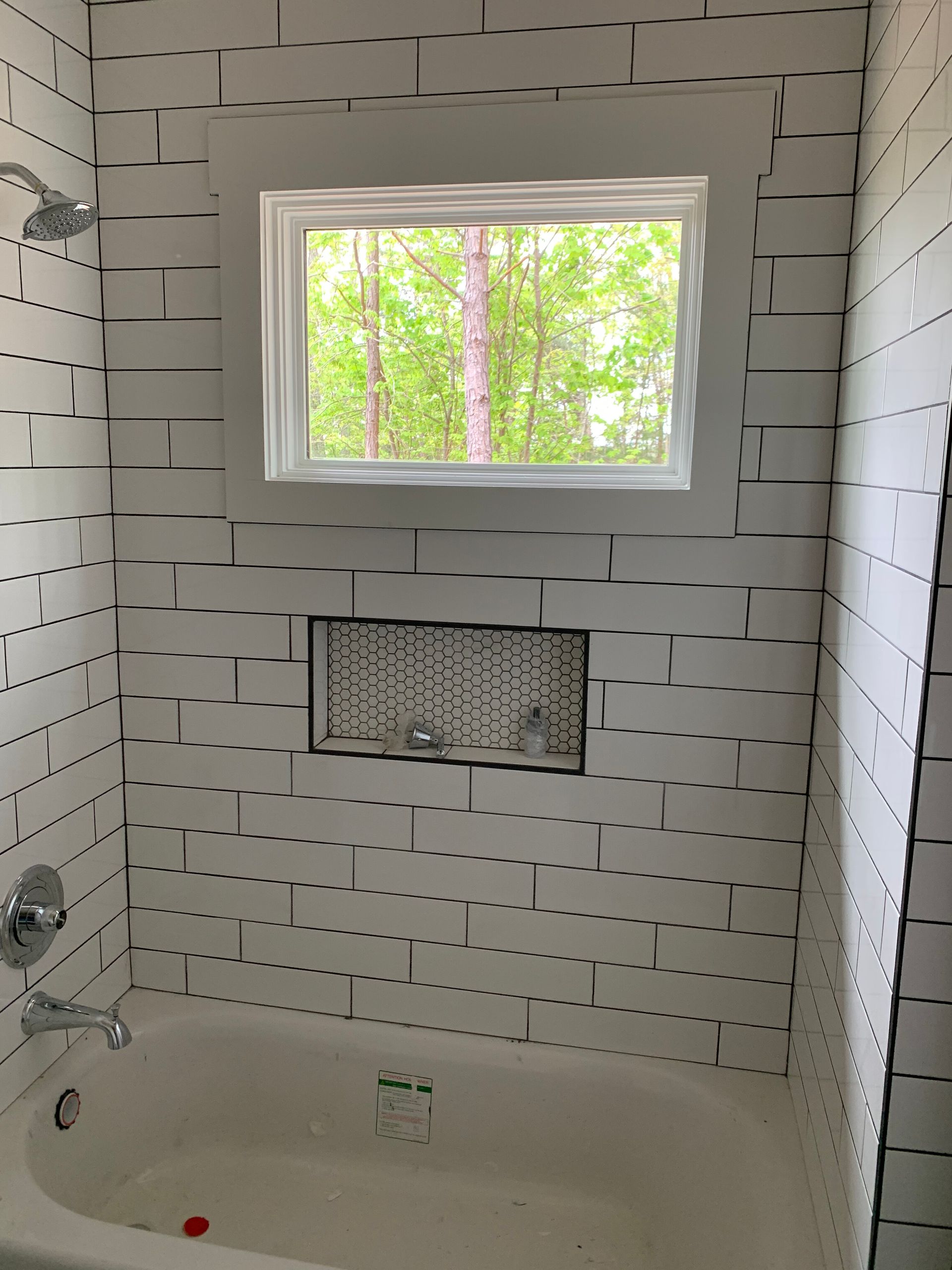 White tiled bathtub with window and built-in niche in a bathroom