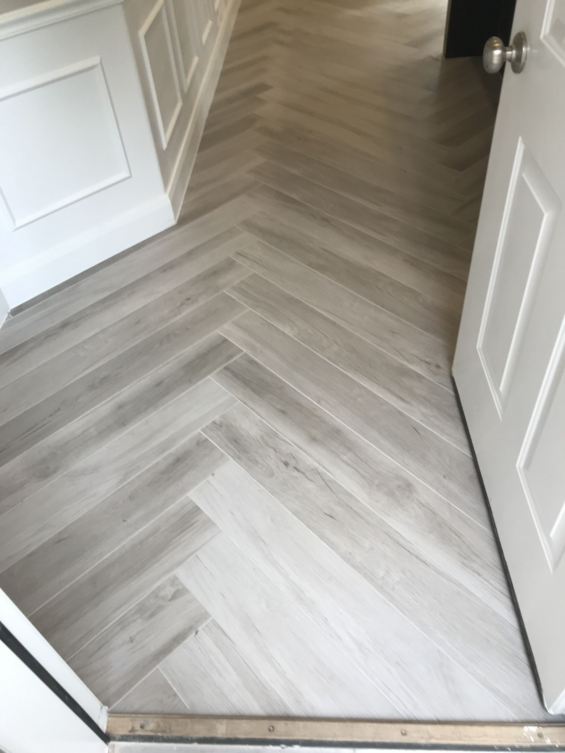 Open doorway to a light wood herringbone floor hallway