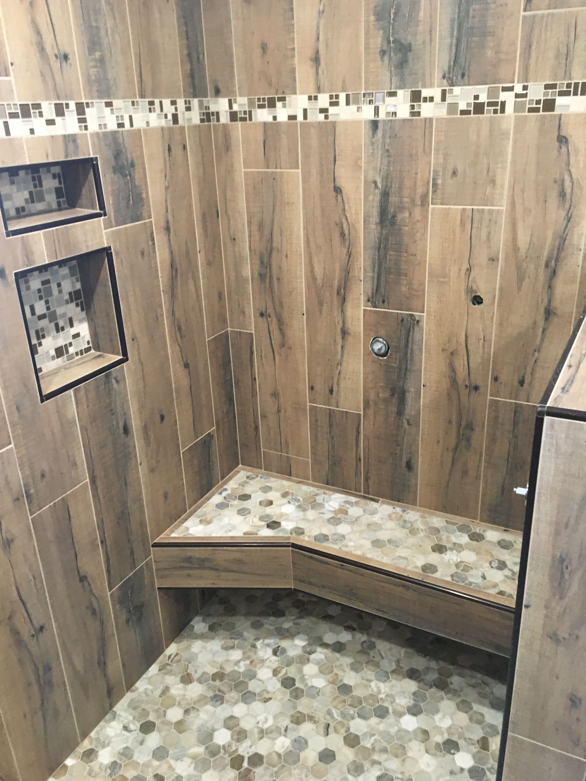 Wood-paneled shower stall with built-in bench and tiled floor