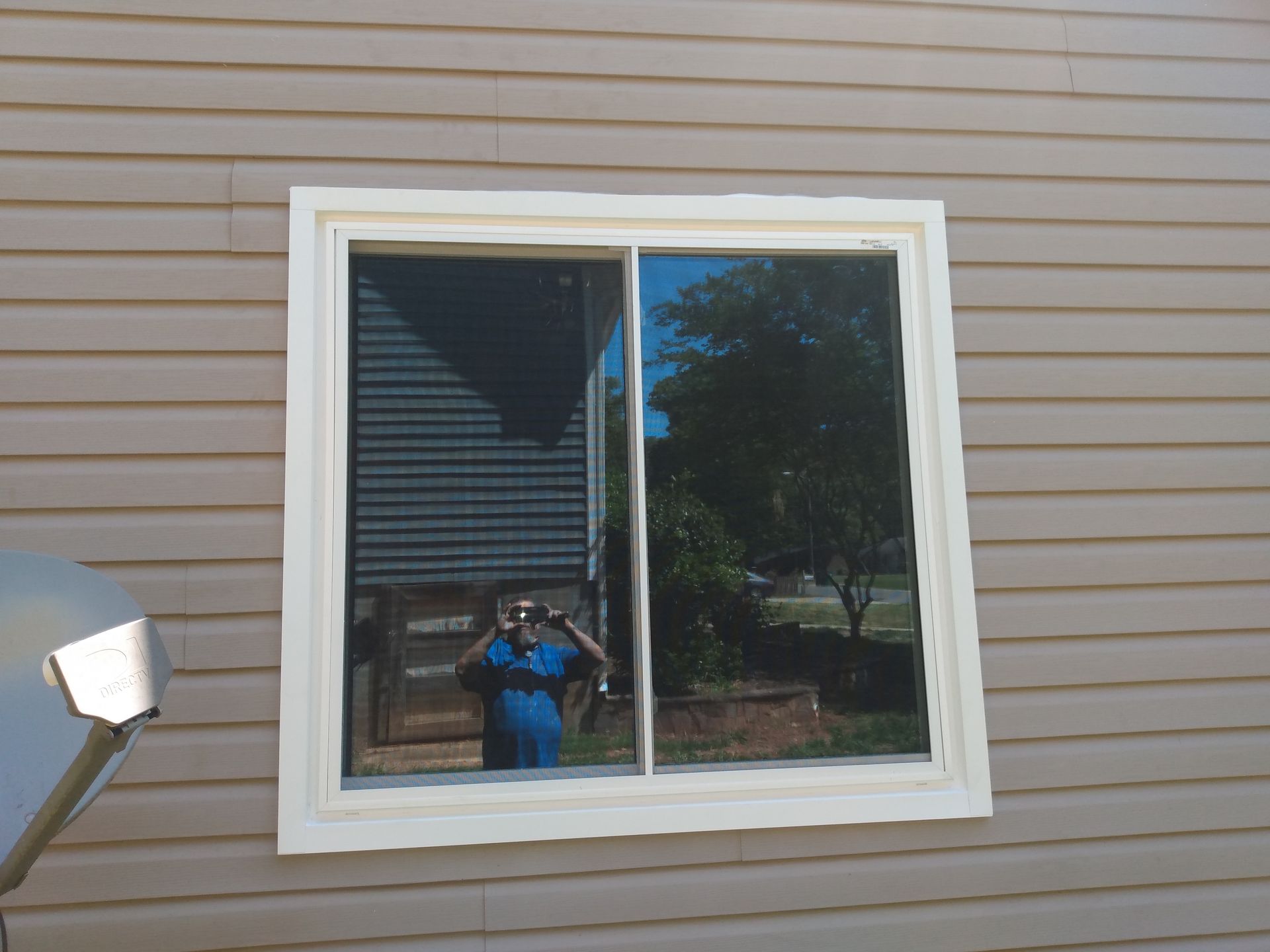 A reflective sliding window on a building with horizontal siding.