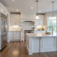 A modern kitchen with white cabinets, granite island, stainless appliances, hardwood floors, and pendant lights over the island.