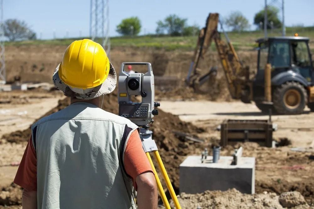 Surveyor in Yellow Hard Hat Using a Total Station at a Construction Site — Coastal Surveying Group Pty Ltd In Baringa, QLD