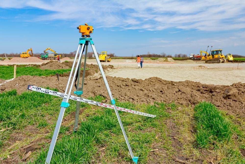 Survey Tripod on a Construction Site With Excavators and Dirt Piles — Coastal Surveying Group Pty Ltd In Baringa, QLD