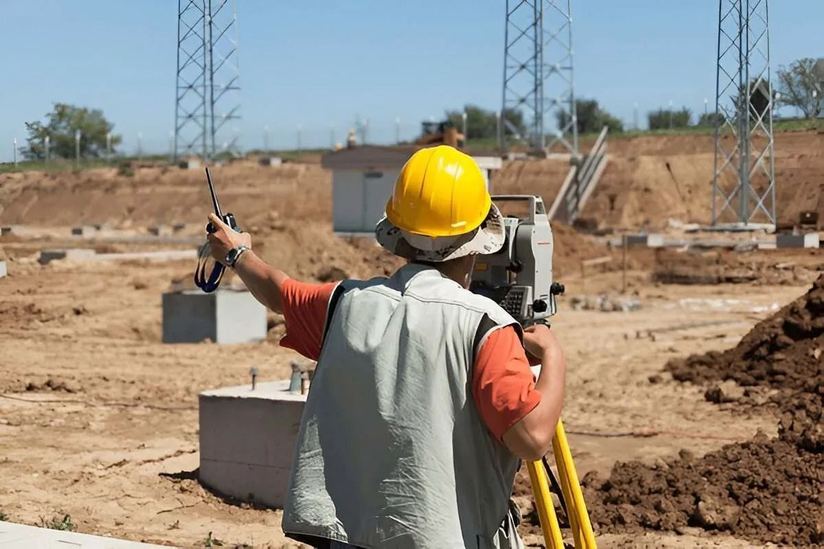 Worker in a Yellow Hard Hat Surveying a Construction Site — Coastal Surveying Group Pty Ltd In Moreton Bay, QLD