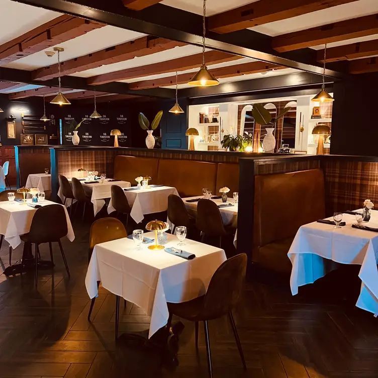 Elegant restaurant dining room with white tablecloths, dark wood booths, and warm pendant lighting