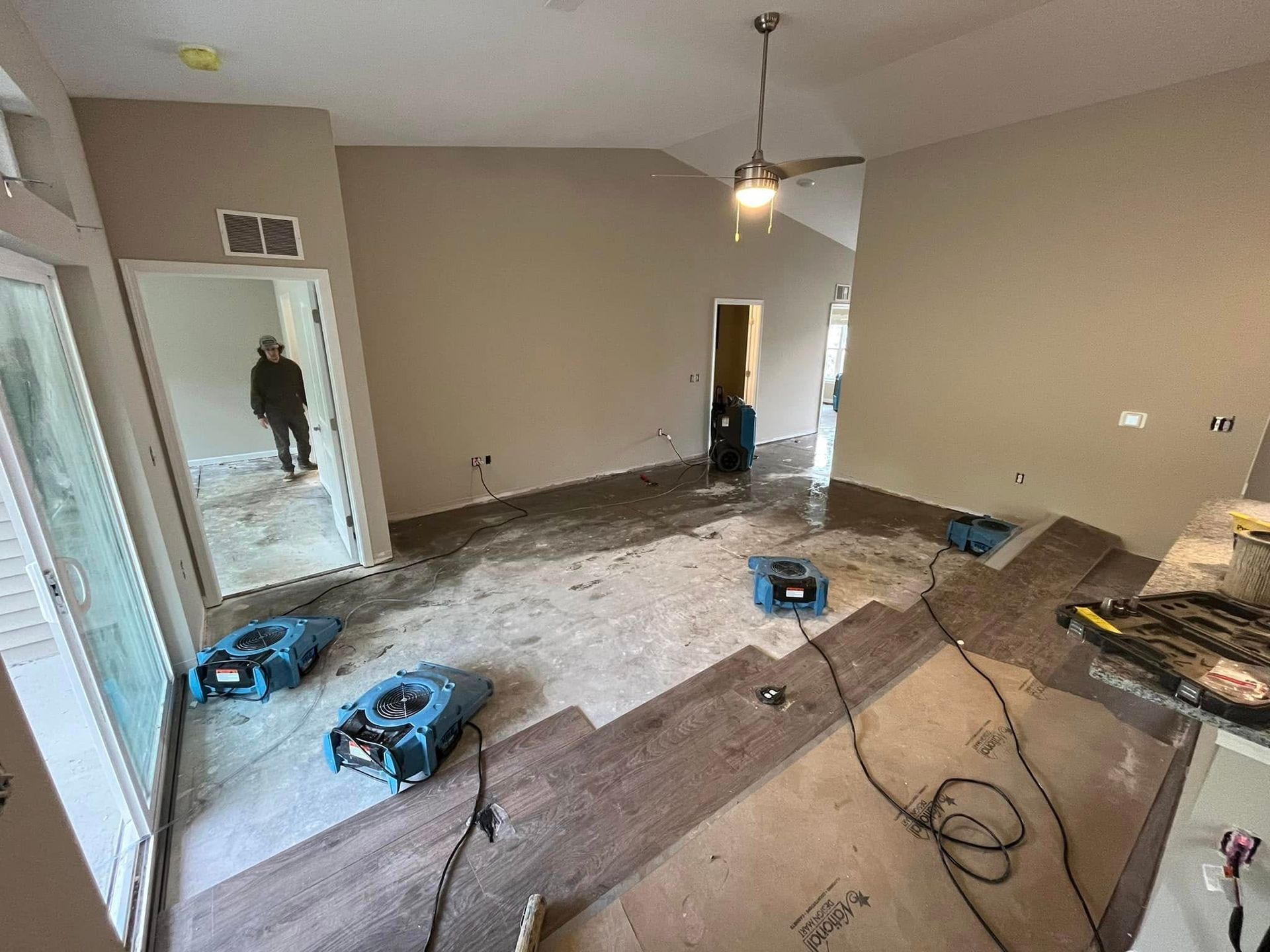 Renovation in progress in an empty room with tools, cords, and unfinished flooring.