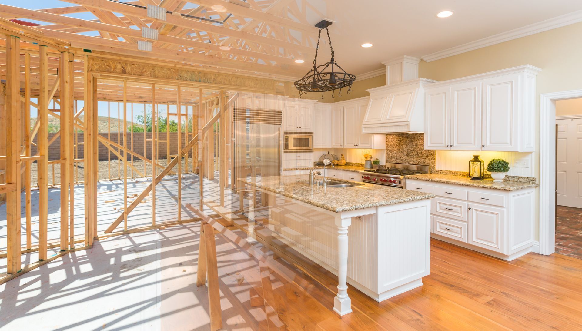 Kitchen under construction with exposed wooden framing, white cabinets, granite island, and sunlit hardwood floors