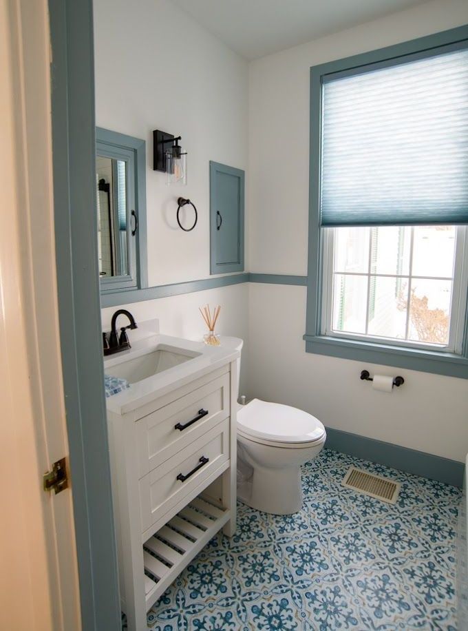Small bathroom with white vanity, toilet, blue trim, and patterned blue-and-white floor tiles.
