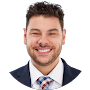 Headshot of a smiling man in a white shirt, blue tie, and dark jacket on a white background