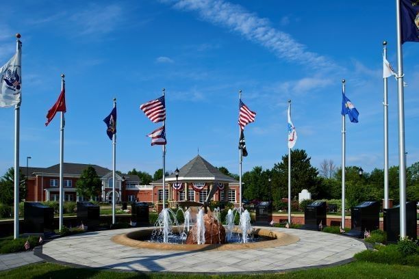 Flags around a fountain in front of a brick building under a blue sky