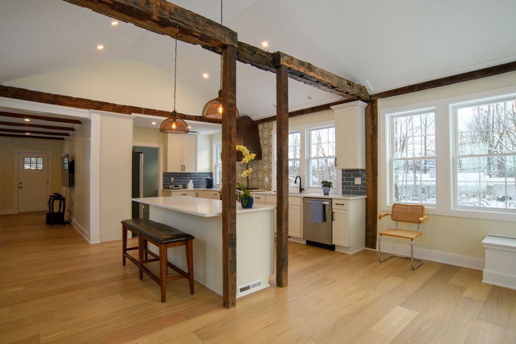 Bright open living room with wood floors, exposed beams, and large windows