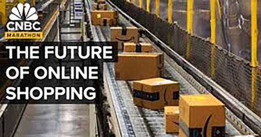 Amazon boxes are moving down a conveyor belt in a warehouse.