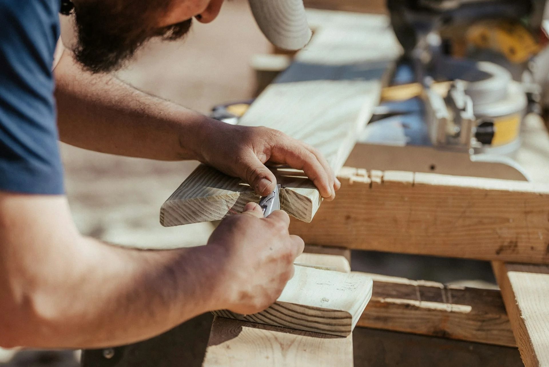 Carpenter planing a wooden board on a workbench in a workshop