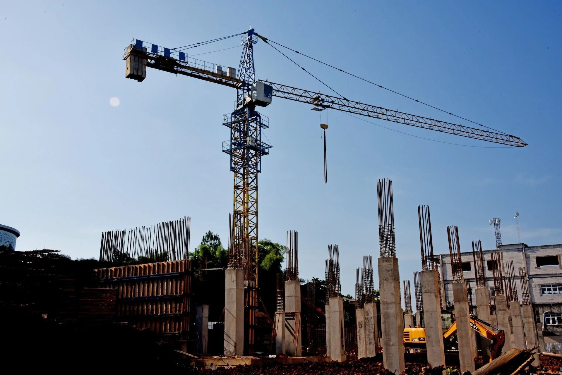 Construction site with tower crane and concrete structures against a blue sky