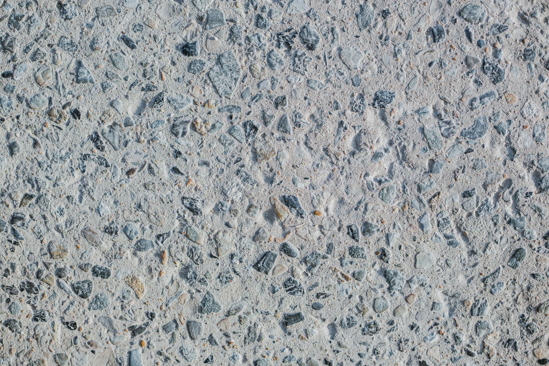 Close-up of gray speckled stone or concrete texture with small dark and light flecks