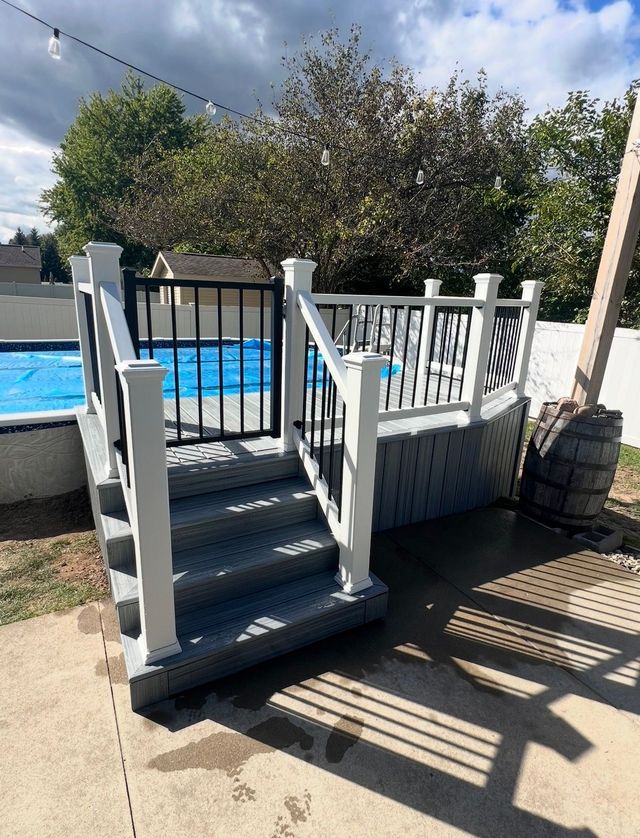 White wooden ramp with railings beside a backyard swimming pool under a sunny sky