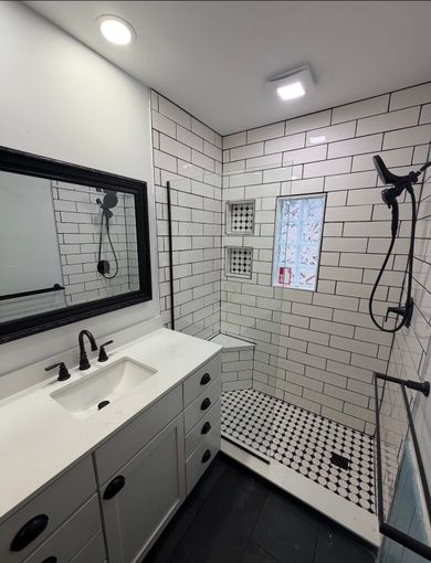 Modern black-and-white bathroom with vanity, tiled shower, window, and rain showerhead