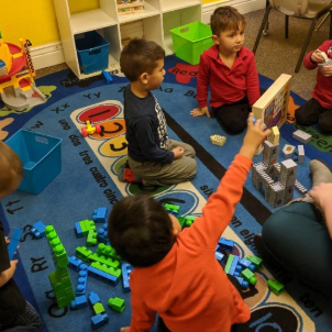 A group of children are playing with toys on a rug that says ry